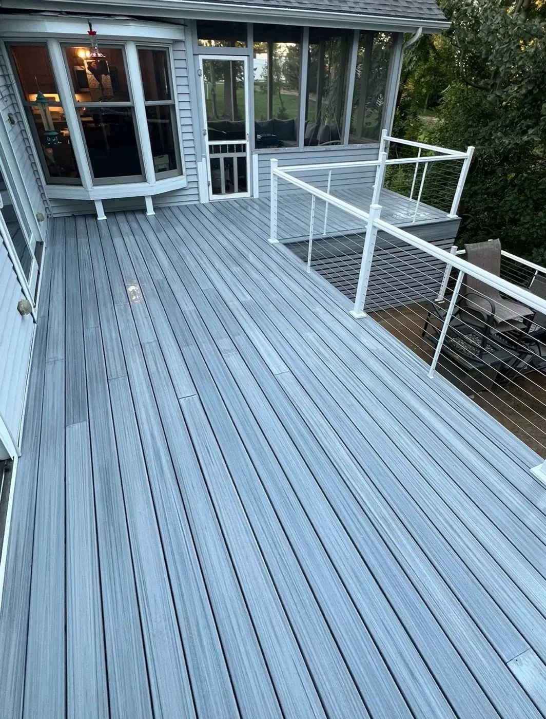 Clean grey composite deck with white railing attached to a house