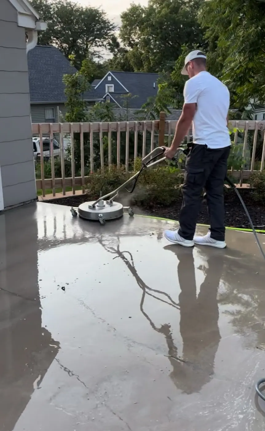 SurfacePro technician cleaning a concrete patio with a surface cleaner